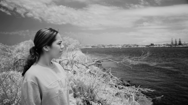 A photograph of a young Aboriginal woman looking out to the coast.